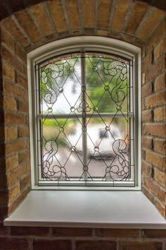 a window that is in the side of a brick wall with a glass design on it