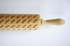 a wooden rolling pin with holes in it on a white surface, showing the handle