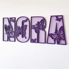 the word art spelled with purple butterflies on a white wall in front of a white background