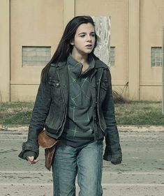 a young woman walking down the street with her hand in her pocket and holding a purse