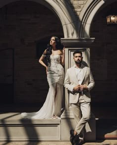 a man and woman standing next to each other in front of a building with arches