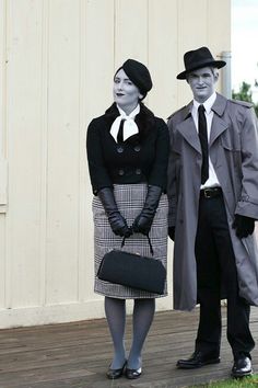 a man and woman dressed up in old fashioned clothing standing next to each other on a wooden deck