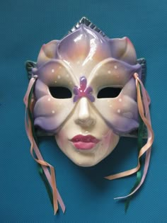 a white mask with purple flowers on it's face and ribbon around the mouth