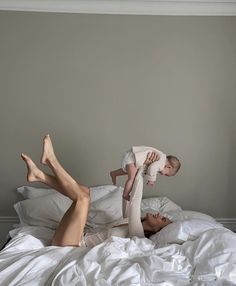 a woman laying on top of a bed holding a baby