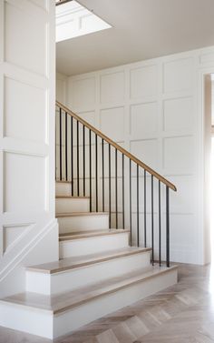 an open door leading to a set of stairs with white walls and wood handrails