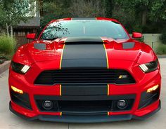 the front end of a red sports car with yellow stripes on it's hood