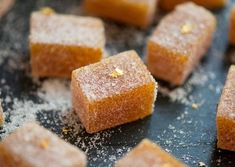 some sugar cubes are sitting on a black surface with sprinkles around them