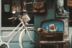 a bicycle parked in front of a building next to a suitcase and bag on the ground