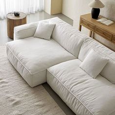 a large white couch sitting on top of a rug next to a table and lamp