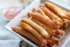 some fried food on a white plate with dipping sauces in the backgroud