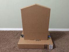 an open cardboard box sitting on the floor next to a white wall and brown carpet