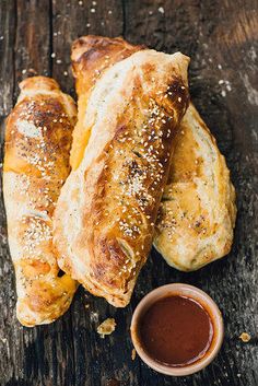 two pieces of bread and dipping sauce on a wooden table