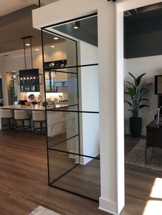 an open living room and kitchen area in a house with wood floors, white walls and black glass doors