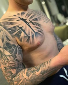 a man with a cross tattoo on his chest holding a cell phone in his hand