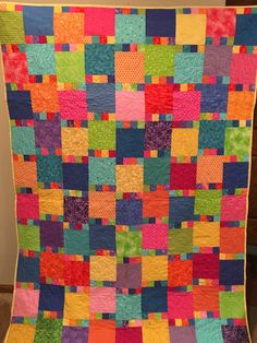 a multicolored quilt hanging on the wall