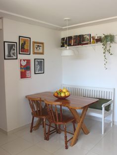 a table with fruit on it in front of a bench and pictures hanging on the wall