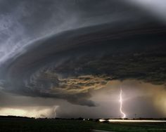 a large storm cloud with lightning in the distance