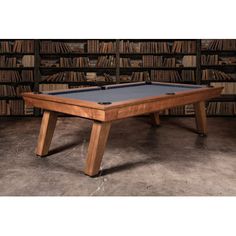 a pool table sitting in front of a bookcase