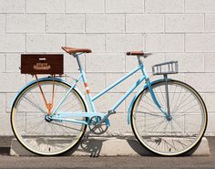 a blue bicycle parked next to a white brick wall with a wooden sign on it