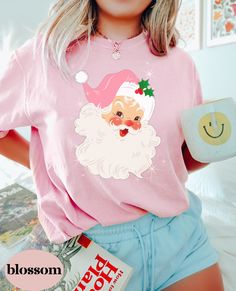 We hope you love this Vintage Santa with a pink hat as much as we do! Comfort Colors shirts are well loved for a reason. They are garment-dyed and 100% ring-spun cotton, resulting in a super soft, very high quality shirt, they quickly become your favorite tees.  UNISEX T-SHIRTS - Women typically wear one size down for a fitted look. Please order 2 sizes up for an oversized look. For the perfect fit measure your favorite shirt and compare it to our size chart. How you order- Select your size and Novelty Pink Crew Neck T-shirt, Trendy Christmas T-shirt Crew Neck, Trendy Christmas Crew Neck T-shirt, Pink Novelty T-shirt With Funny Print, Pink Novelty Crew Neck T-shirt, Pink Crew Neck Novelty T-shirt, Cute Winter Tops As Gift, Cute Winter Tops As A Gift, Pink Graphic Print T-shirt For Holiday