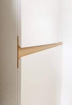 the corner of a white cabinet with a wooden shelf on it's left side