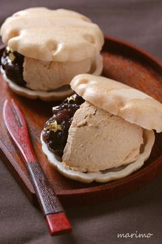 two ice cream sandwiches are on a wooden plate with a red handled utensil