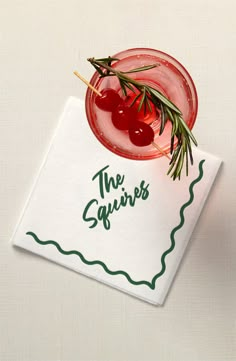 a napkin with an olive and cherry cocktail on it