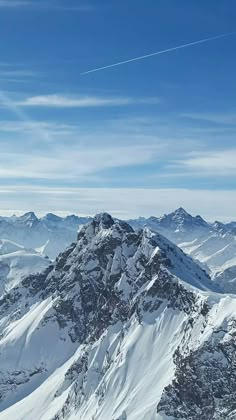 a person on skis standing on top of a snow covered mountain with mountains in the background