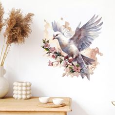 a white dove with pink flowers on it's back wall