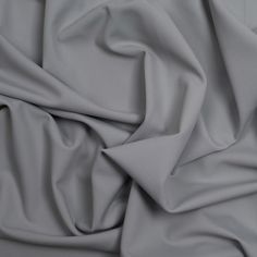 a close up view of a plain grey fabric with very soft folds and wrinkles