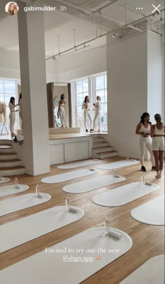 a group of women standing in front of a room with lots of white rugs on the floor