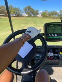 a person driving a golf cart with a gps on the steering wheel and paper in their hand