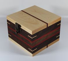 a wooden box with red and black strips on it's sides, sitting on a white surface