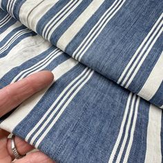 a person holding onto a blue and white striped fabric with their hand on the edge