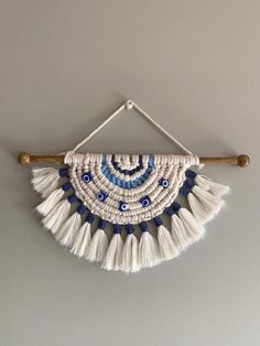 a white and blue wall hanging on a gray wall with two wooden sticks attached to it