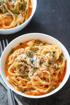 two bowls of spaghetti with sauce and parmesan cheese