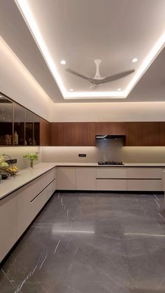 a large kitchen with white cabinets and marble flooring is lit by recessed lighting