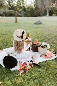 a woman sitting on top of a grass covered field next to watermelon slices