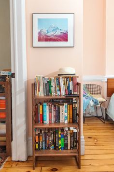 a bookshelf filled with lots of books next to a bed in a room