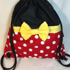 a red and white polka dot bag with a yellow bow on the front, sitting on a white surface