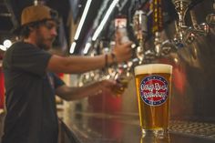 a man standing at a bar with a pint of beer