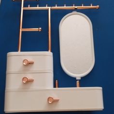 a white and gold bathroom set on a blue surface with copper fittings around it