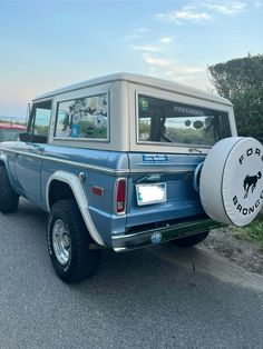 a blue truck parked on the side of a road with a sign attached to it's back