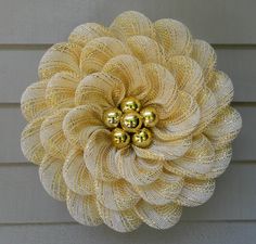 a yellow flower made out of mesh on the side of a building with gold balls