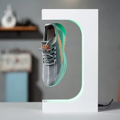 a pair of sneakers hanging from the side of a white box on top of a table