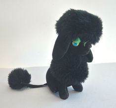 a black stuffed animal sitting on top of a white table next to a green eye