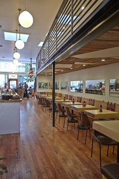 the inside of a restaurant with wooden floors and lots of tables on each side of the room