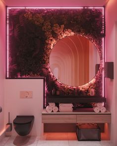 a bathroom with a mirror, sink and toilet in the corner next to a plant covered wall