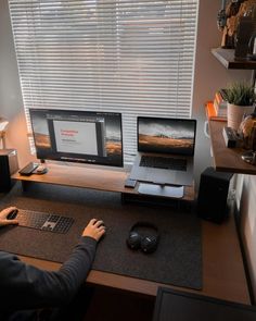 a person sitting at a computer desk with two monitors and a keyboard in front of them