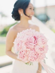 a woman in a wedding dress holding a bouquet of pink peonies on instagram